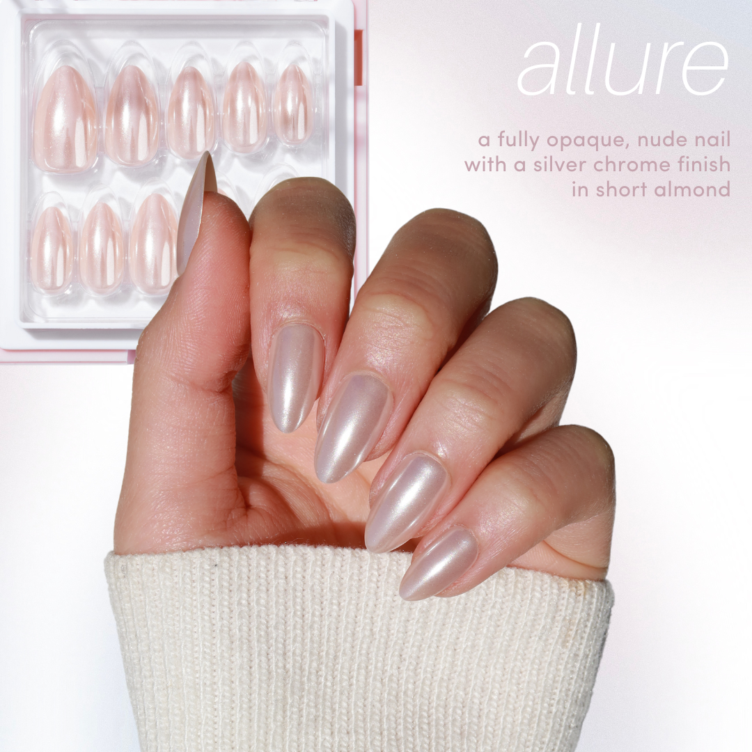 A hand displays chic, short almond-shaped nails in a nude shade with a mesmerizing silver chrome finish against a gentle white background. The packaging presents extra nails. Text reads: "allure, a fully opaque, nude nail with a trendy cat eye chrome finish." From the 11:11 Collection Vol. 2 by Glowie By Her (25% Off).