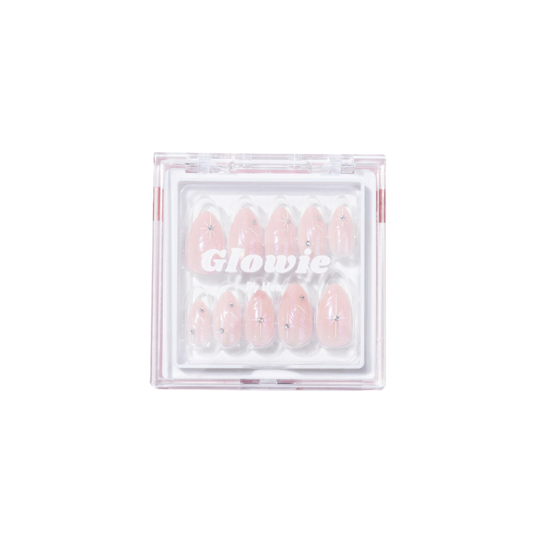 A transparent box contains a set of reusable, glossy almond nails in rose pink with silver starry designs. The word "Glowie By Her" is centered on the box's lid. Inside the box, the Aura Press-On Nails are arranged in two rows.