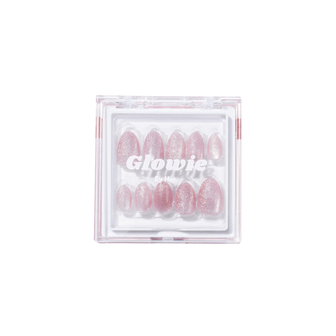 A set of salon-quality, glittery light mauve-pink press-on nails, named "Celestial," is displayed in a clear plastic case. These nails from Glowie By Her are 100% customizable and arranged by size from large to small. The case prominently showcases the "Glowie By Her" label in sleek white text.