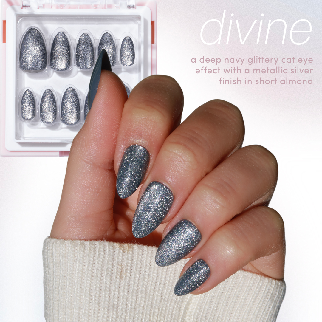 A hand with a cream-colored sweater sleeve flaunts short almond-shaped nails adorned in a glittery deep navy shade. Above, there is a display of complementary cat eye nails. Text reads: "11:11 - Full Collection by Glowie By Her - featuring divine, a deep navy glittery cat eye effect with a metallic silver finish. Grab it at 35% off during the Black Friday Sale!