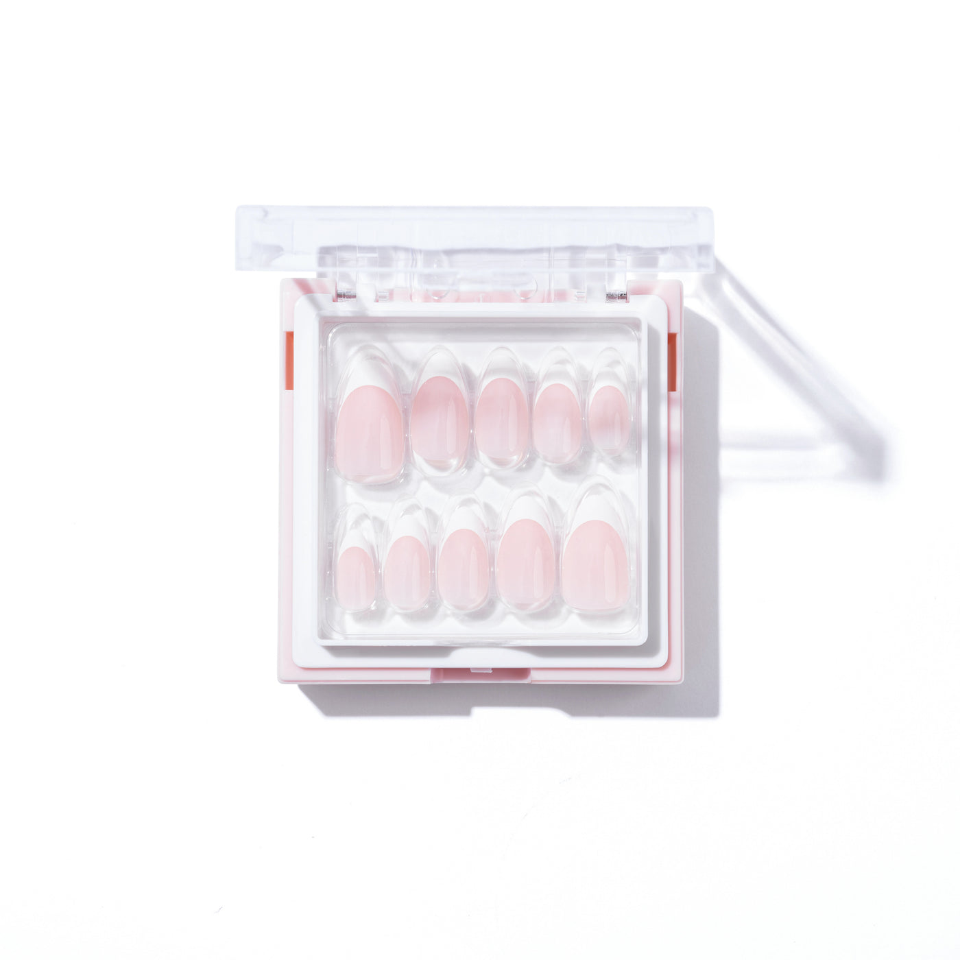 An open box of 'That girl' Press-On Nails by Glowie Co. features pink, short nails meticulously arranged in rows according to size. The box has a clear top and a white base, and the shadows hint at a light source from one side. The organized layout beautifully displays these salon-quality nails in a gradient of sizes.