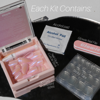 The Glowie By Her Skye Press-On Nails kit includes 30 salon-quality nails in varying sizes, a tube of nail glue, a cuticle stick, an alcohol pad, a nail file, and sticky tabs. The nails feature a pink pearlescent finish. Each kit is packaged in reusable Glowie cases and offers 100% customization.