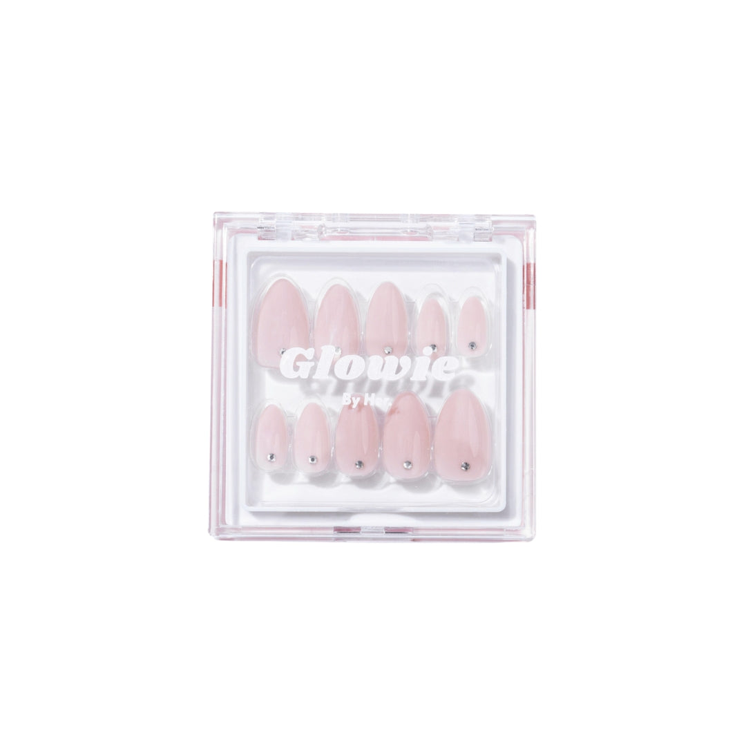 A clear plastic box containing a set of Laura Press-On Nails in baby pink with small rhinestone accents. The transparent lid features the text "Glowie By Her" in white lettering, and the salon-quality nails are neatly arranged inside.