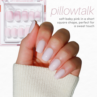 A hand with a light skin tone, wearing a beige ribbed sleeve, displays short, square-shaped nails painted in a soft baby pink color. Above and to the right, text reads "pillowtalk" and "soft baby pink in a short square shape, perfect for a sweet touch." Featuring chrome nail styles from Glowie By Her's Essentials Collection 2.0 (20% Off).