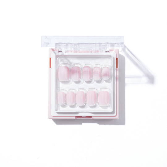 The Pillowtalk set from Glowie By Her comes in a square case containing ten pink artificial nails, arranged in two rows and varying in size. The case has a transparent lid set against a minimalist white background, offering versatile salon-quality nails perfect for customizable styles.