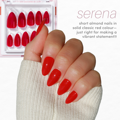 A hand with short almond-shaped nails painted in solid classic red is shown. In the background, a pack of similar red false nails from the Essentials Collection 2.0 by Glowie By Her is partially visible. The text reads "serena: short almond nails in solid classic red colour—just right for making a vibrant statement!" Enjoy 20% off!