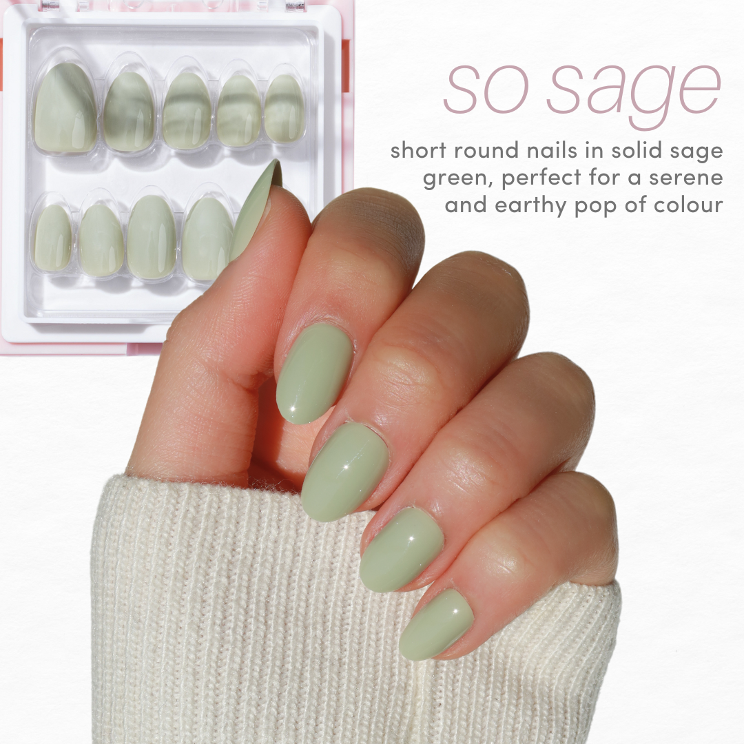 A hand with short, round nails painted in a solid sage green color, displayed over a light background. In the upper left is a bundle of matching false nails from Glowie By Her's Essentials Collection 2.0 (20% Off). Text reads: "so sage - short round nails in solid sage green, perfect for a serene and earthy pop of color.