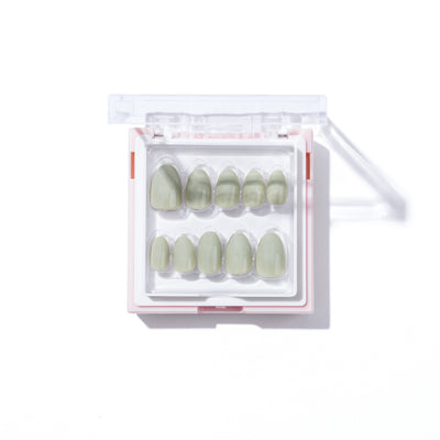 The So Sage Press-On Nails from Glowie By Her are arranged neatly in a white and pink plastic case with a clear lid. These salon-quality, vegan, and cruelty-free green false nails are displayed in two rows, varying in size from large to small, and are securely held in place within the case.