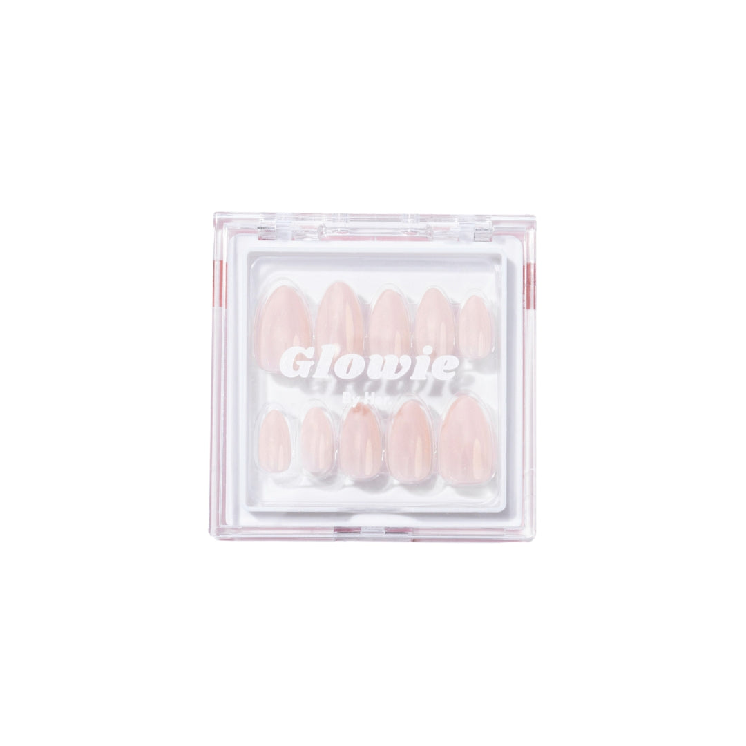 A clear plastic box labeled "Vanilla Press-On Nails" by Glowie By Her displays a set of salon-quality, baby pink press-on nails with a glossy, oval shape, arranged neatly in rows. The background is white, and the packaging is transparent, showcasing the nails inside.